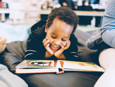 Young boy reading with a smile on his face